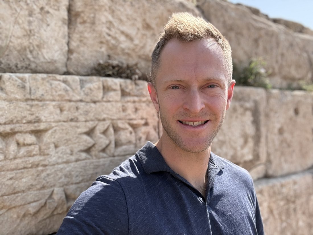 Jamie Watt standing in front of the carved stone blocks of King Sennacherib's aqueduct