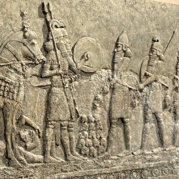 A carved stone relief of Assyrian soldiers marching with spears and a shield