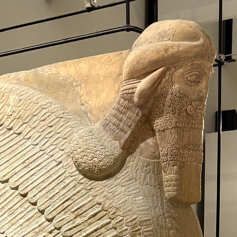 Close view of the carved head and wing of a lamassu, an Assyrian figure that is part bull, part eagle, part human